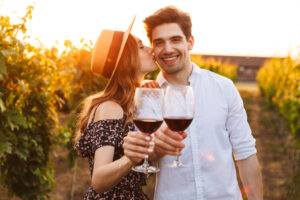 Photo of young cute happy loving couple outdoors drinking wine looking at camera.